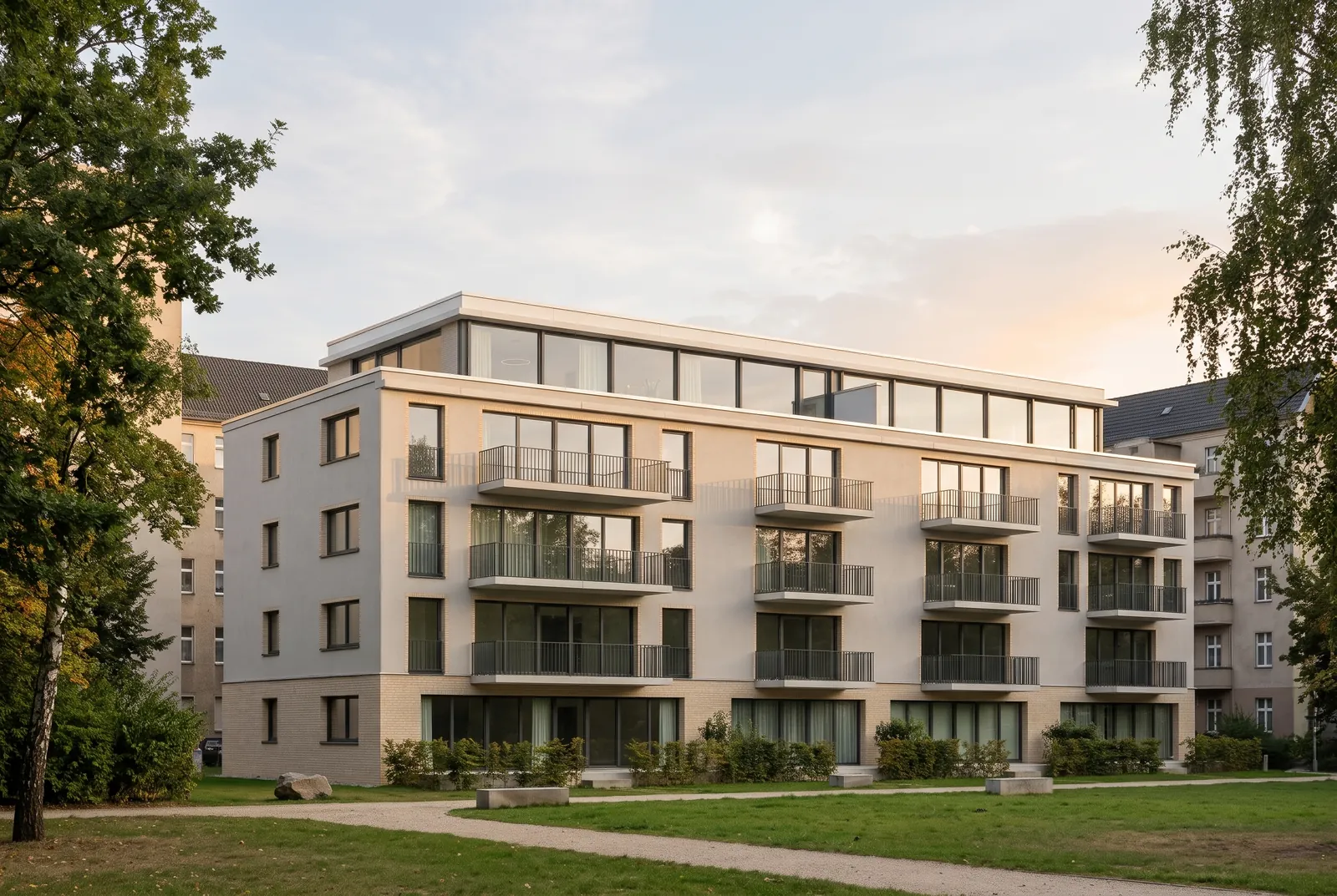 Orvenhof in evening light: five-storey apartment building with a clinker plinth, balconies and a set-back top floor at the edge of a city park — illustrative visualisation
